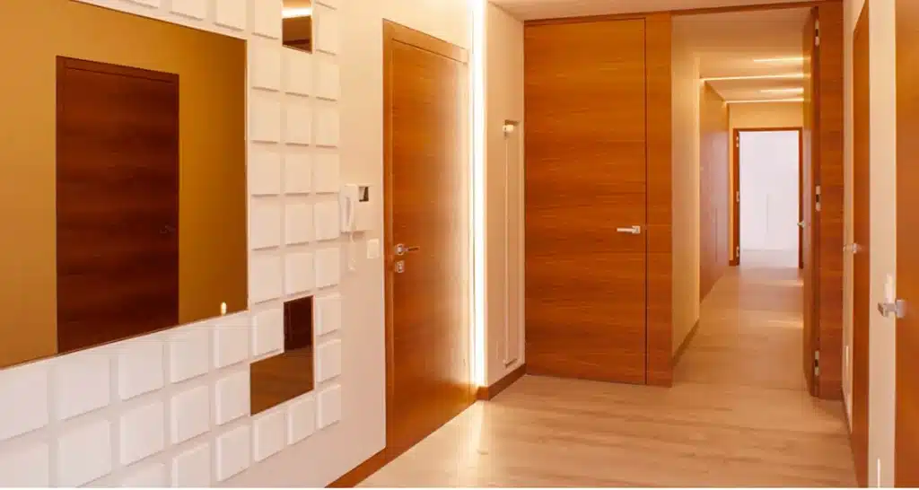 Contemporary hallway featuring warm wood doors, a white 3D geometric wall panel, and a bronze-tinted mirror.